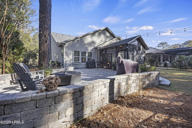 rear view of house featuring a fire pit, a sunroom, and a patio