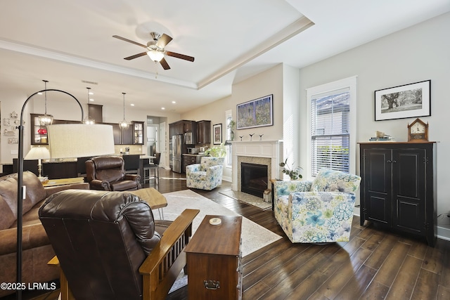 living room featuring dark hardwood / wood-style floors, a raised ceiling, and ceiling fan