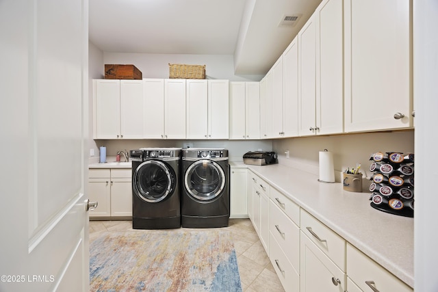 laundry room with cabinet space, light tile patterned floors, visible vents, washer and dryer, and a sink