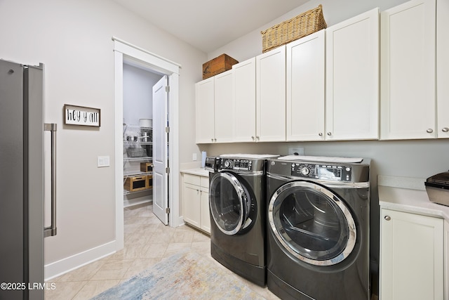 washroom featuring light tile patterned flooring, cabinets, and washing machine and clothes dryer