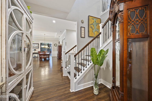 entryway with a chandelier, recessed lighting, dark wood-style flooring, stairs, and a raised ceiling