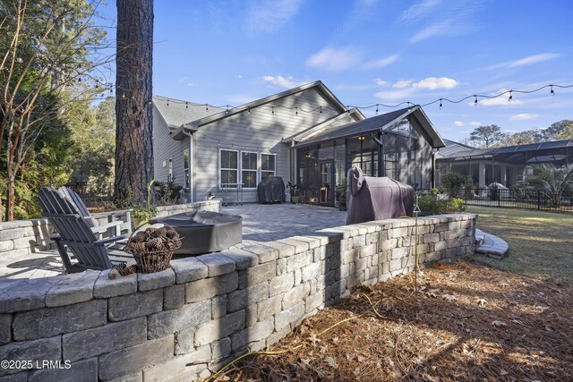 rear view of property with an outdoor fire pit, a sunroom, and a patio