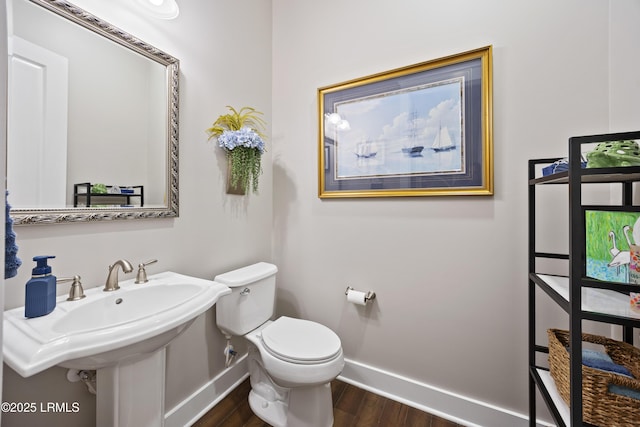 bathroom with toilet, a sink, baseboards, and wood finished floors