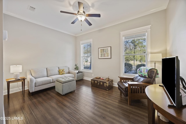 living room with ornamental molding, dark wood-type flooring, and ceiling fan