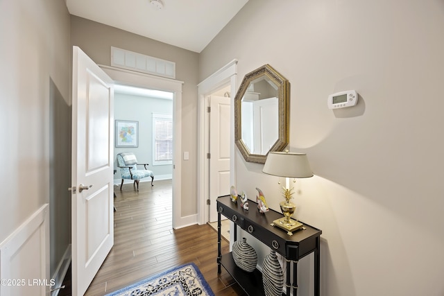 hall with dark wood-style flooring and baseboards