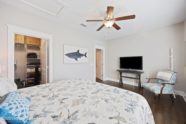 bedroom with ceiling fan, a walk in closet, dark wood-type flooring, and a closet