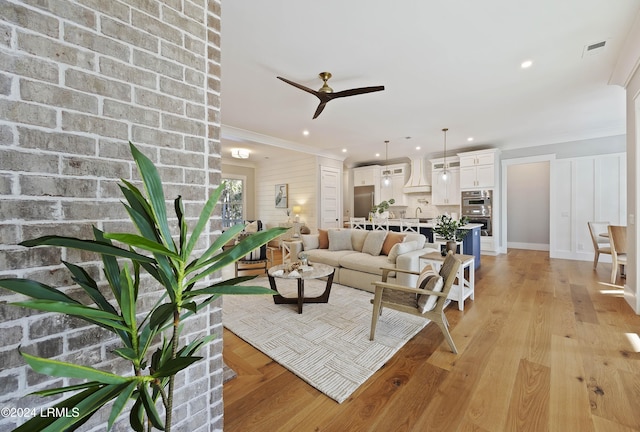 living room with ceiling fan, ornamental molding, and light hardwood / wood-style floors