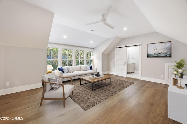 living room with hardwood / wood-style flooring, vaulted ceiling, a barn door, and ceiling fan