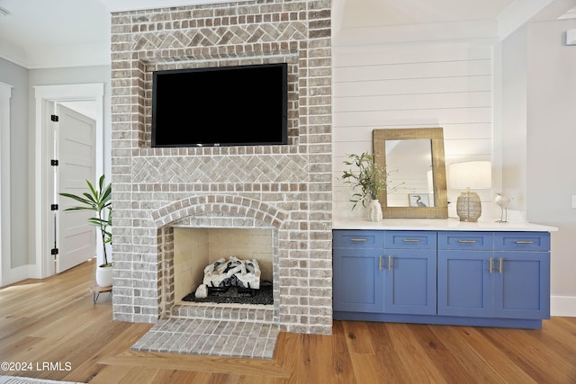 living room with crown molding, a fireplace, and light hardwood / wood-style floors