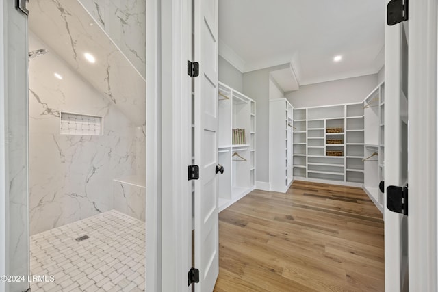 bathroom featuring hardwood / wood-style flooring, tiled shower, and ornamental molding