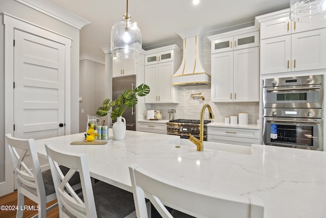 kitchen with backsplash, a breakfast bar area, white cabinets, and premium range hood