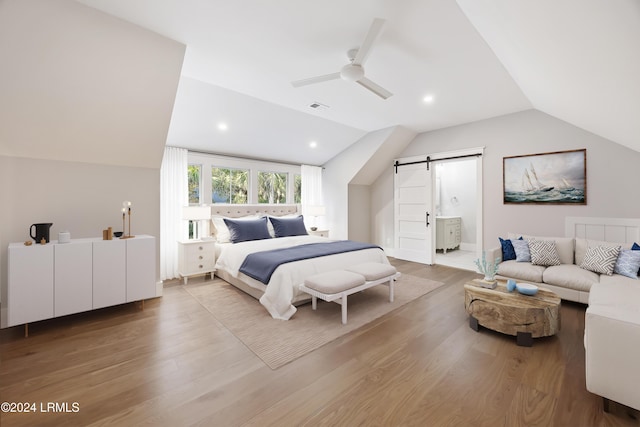 bedroom with vaulted ceiling, a barn door, connected bathroom, and ceiling fan