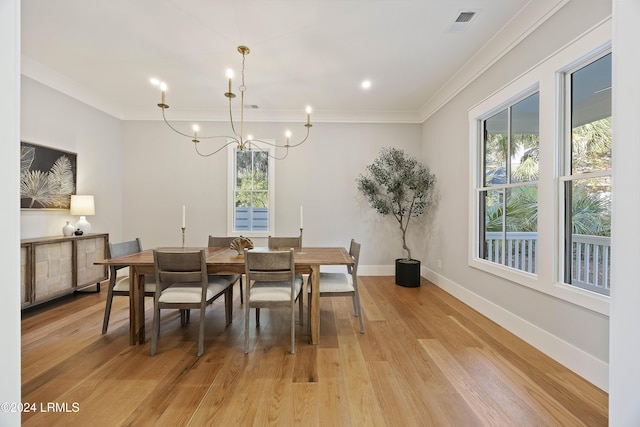 dining space featuring ornamental molding, an inviting chandelier, and light wood-type flooring