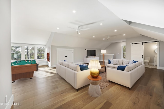 living room with lofted ceiling, billiards, ceiling fan, a barn door, and light wood-type flooring