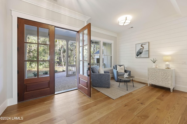 entrance foyer with light hardwood / wood-style flooring, a healthy amount of sunlight, and wood walls