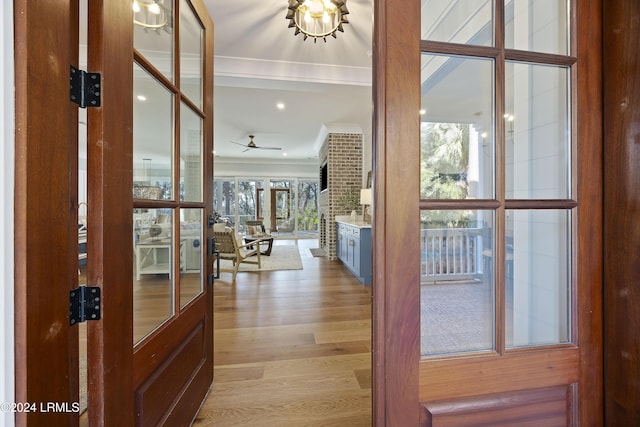 entrance foyer with crown molding, ceiling fan with notable chandelier, and light wood-type flooring