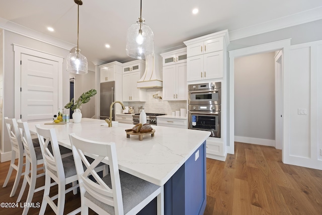 kitchen featuring pendant lighting, an island with sink, and premium range hood