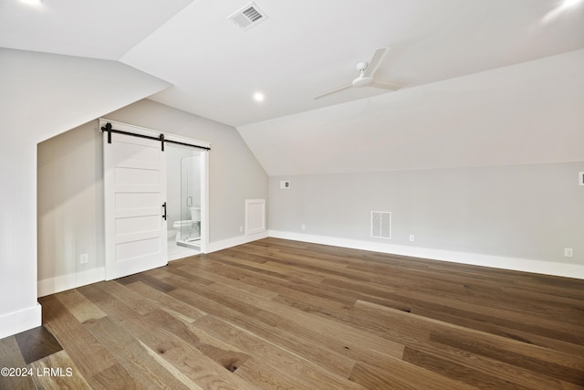 additional living space with hardwood / wood-style floors, vaulted ceiling, a barn door, and ceiling fan