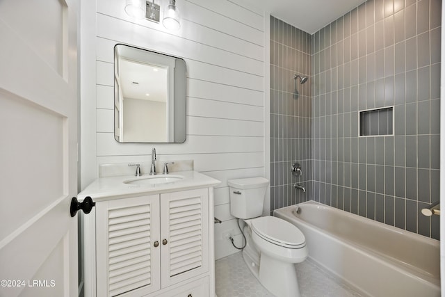 full bathroom with wooden walls, vanity, tiled shower / bath, tile patterned floors, and toilet