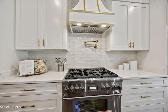 kitchen with white cabinetry, high end range, custom range hood, light stone countertops, and decorative backsplash