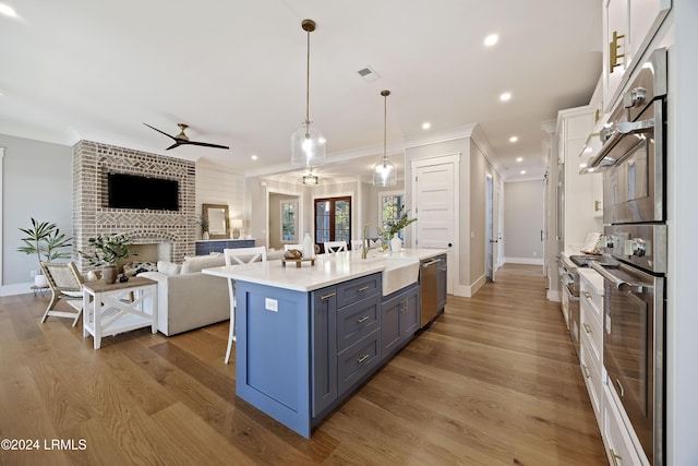 kitchen with pendant lighting, sink, dishwasher, white cabinetry, and a kitchen bar