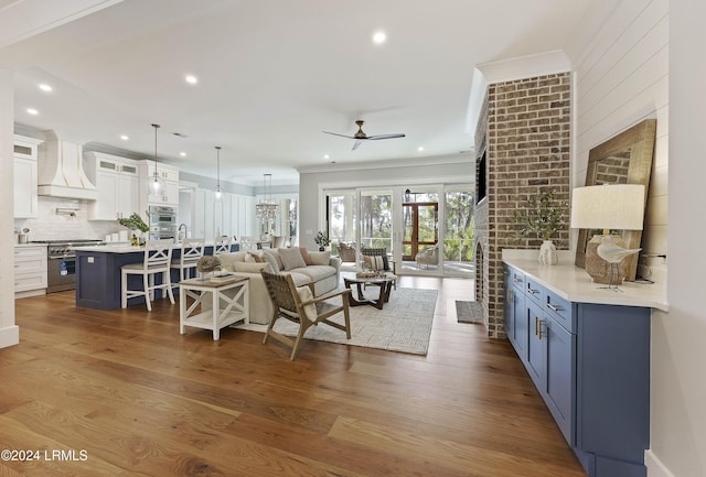 living room featuring hardwood / wood-style flooring, ceiling fan, and crown molding