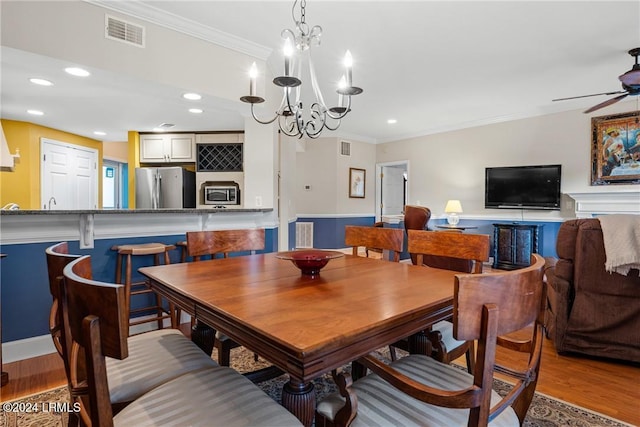 dining room featuring crown molding, wood-type flooring, and ceiling fan with notable chandelier