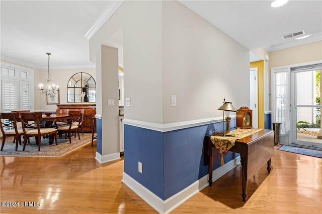 entrance foyer with crown molding, light wood-type flooring, and a notable chandelier