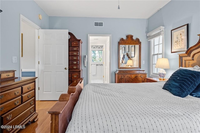 bedroom with connected bathroom and light wood-type flooring