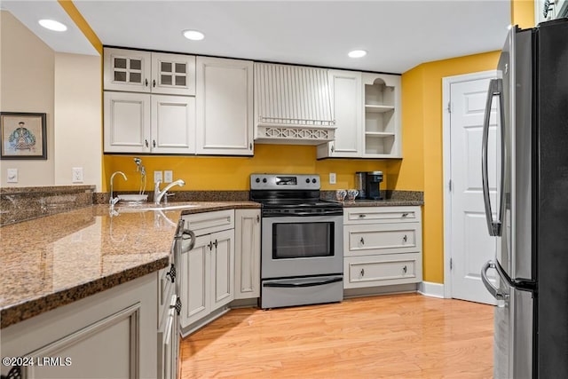 kitchen featuring sink, light hardwood / wood-style flooring, dark stone countertops, stainless steel appliances, and white cabinets