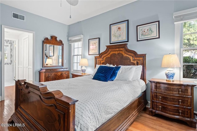 bedroom with ensuite bathroom and light hardwood / wood-style floors