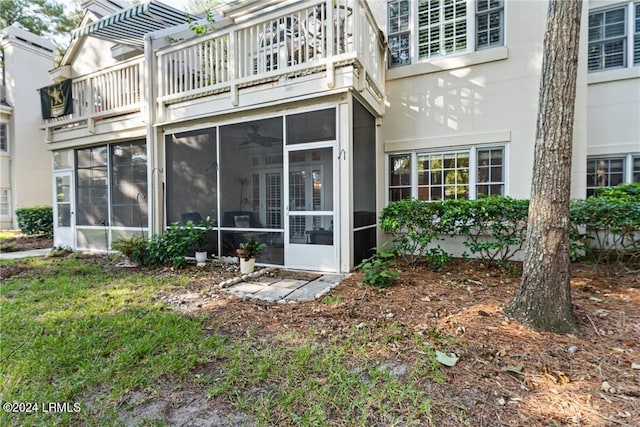 rear view of house featuring a pergola, a sunroom, and a balcony