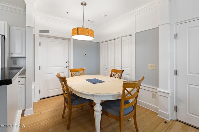 dining space featuring ornamental molding and light hardwood / wood-style floors