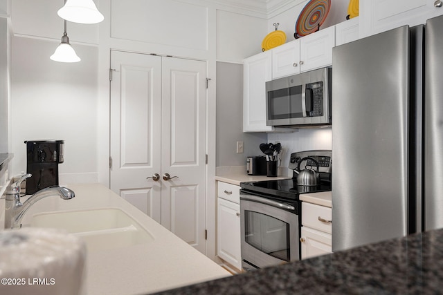 kitchen featuring pendant lighting, sink, white cabinetry, and stainless steel appliances