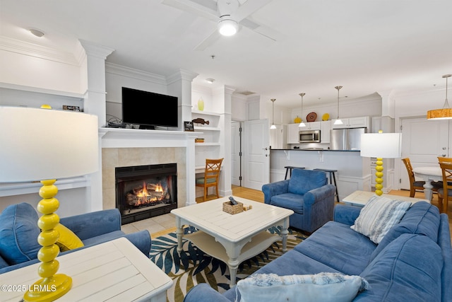 living room with crown molding, a fireplace, and ceiling fan