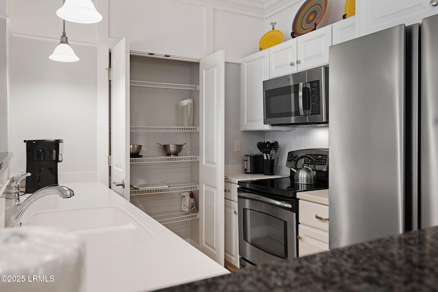 kitchen with stainless steel appliances, hanging light fixtures, sink, and white cabinets