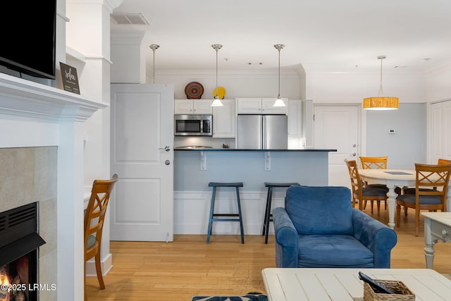 interior space featuring stainless steel appliances, decorative light fixtures, a kitchen breakfast bar, and white cabinets