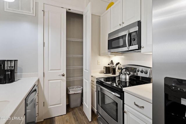 kitchen featuring stainless steel appliances, dark hardwood / wood-style floors, and white cabinets