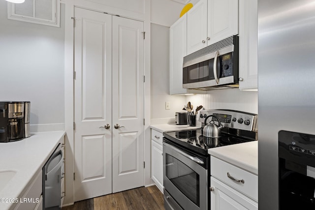 kitchen with appliances with stainless steel finishes, dark wood-type flooring, and white cabinets