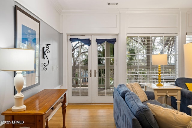 doorway to outside featuring ornamental molding, light wood-type flooring, and french doors