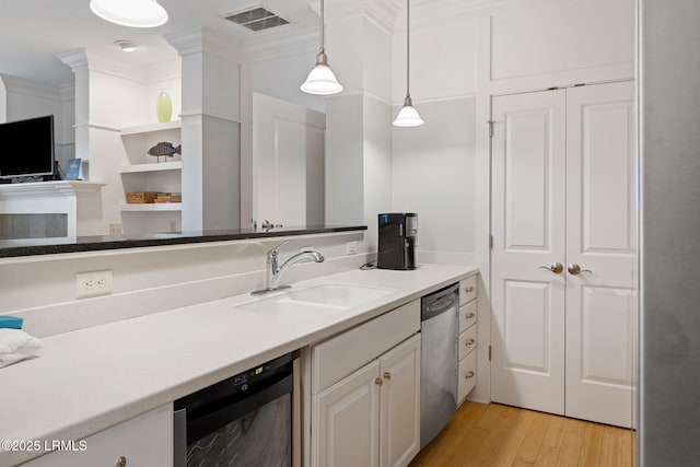 kitchen with crown molding, sink, decorative light fixtures, and stainless steel dishwasher