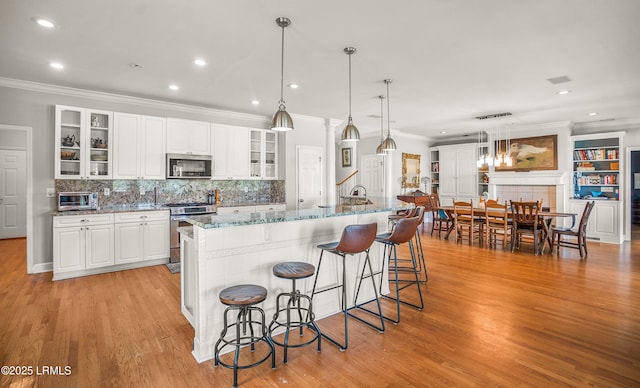 5 Petigru Dr, Beaufort, SC 29902 - kitchen featuring appliances with stainless steel finishes, ornamental molding, light wood-style floors, a kitchen bar, and decorative backsplash