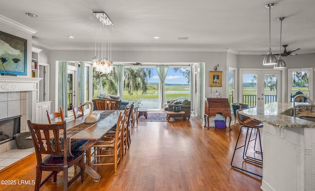 5 Petigru Dr, Beaufort, SC 29902 - dining space with a tiled fireplace, french doors, wood finished floors, crown molding, and a chandelier