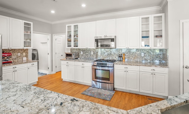 5 Petigru Dr, Beaufort, SC 29902 - kitchen with appliances with stainless steel finishes, backsplash, light wood finished floors, crown molding, and glass insert cabinets