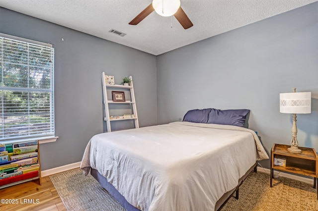 bedroom with light wood-style floors, multiple windows, baseboards, and a textured ceiling