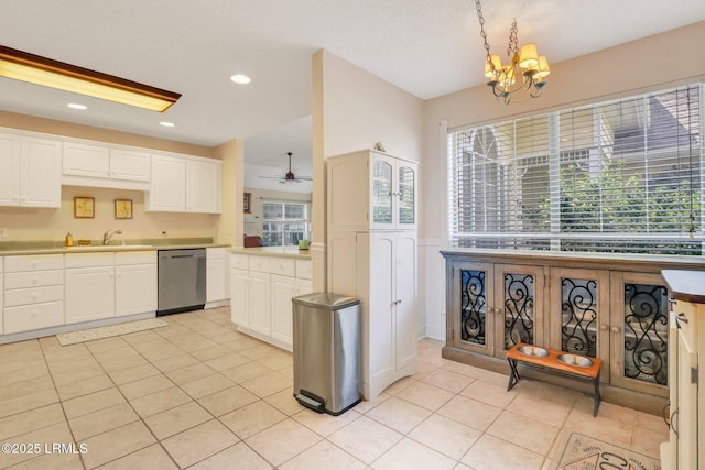 kitchen featuring pendant lighting, light countertops, white cabinetry, a sink, and dishwasher