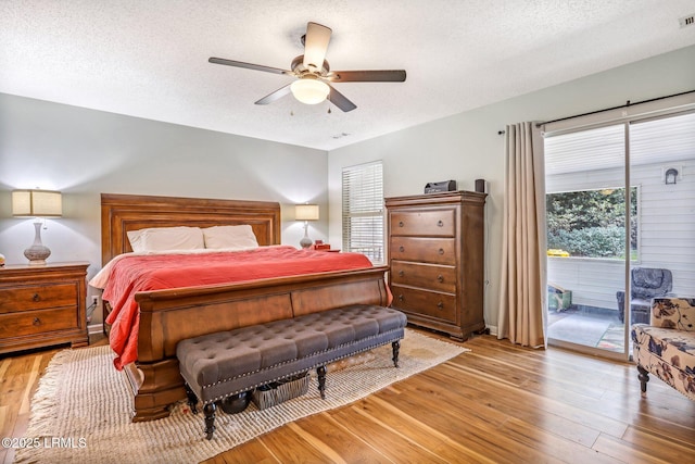 bedroom featuring access to exterior, a textured ceiling, visible vents, and light wood-style floors