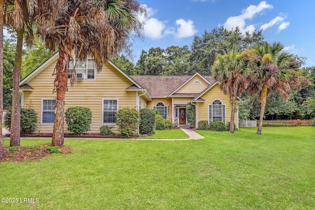 view of front of property featuring a front lawn, a shingled roof, and fence