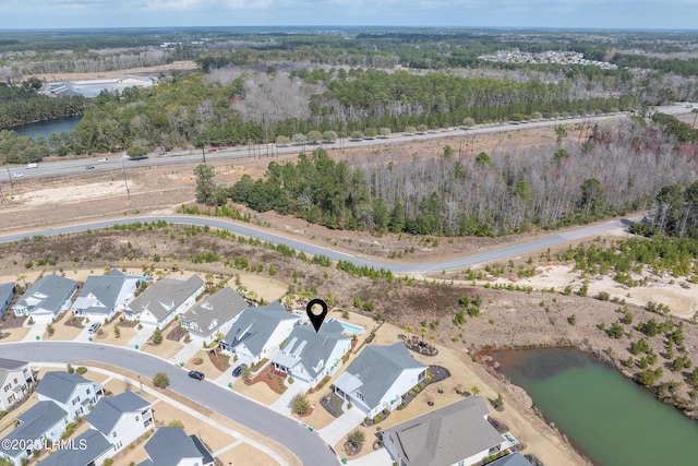 drone / aerial view featuring a residential view, a water view, and a view of trees