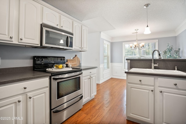 kitchen featuring pendant lighting, sink, white cabinets, stainless steel appliances, and crown molding